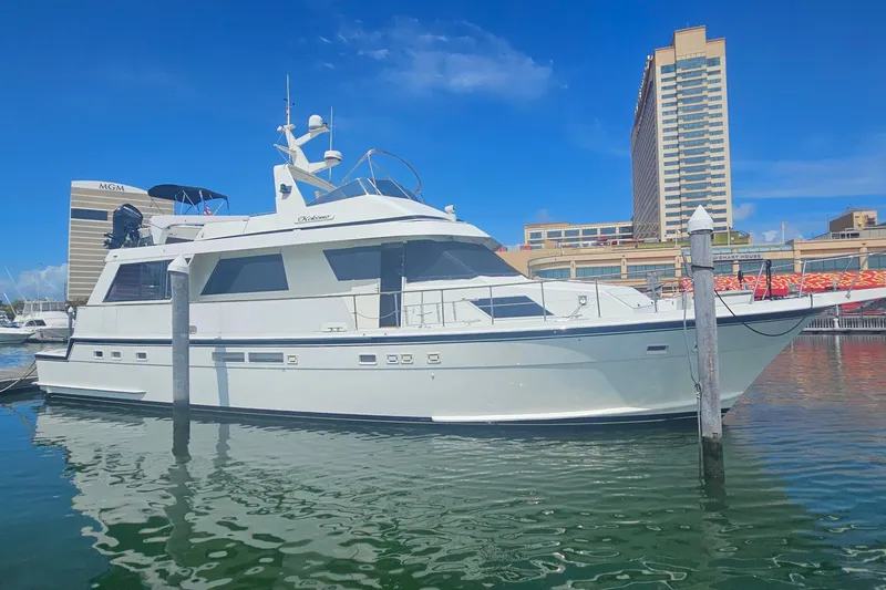 Slide: The Image of 1990 Hatteras 67 Cockpit Motor Yacht docked in a marina, clear blue sky. - 1