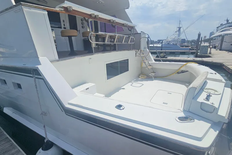 Slide: The Image of 1990 Hatteras 67 Cockpit Motor Yacht docked, featuring spacious deck and seating area. - 10