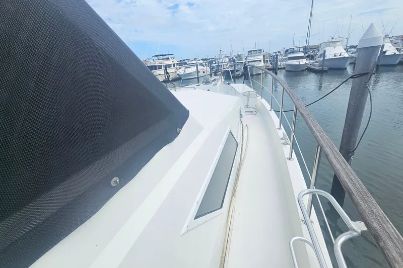Slide: The Image of 1990 Hatteras 67 Cockpit Motor Yacht docked in a marina, side view. - 16