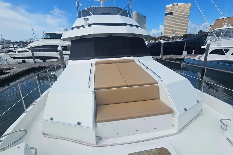 Slide: The Image of 1990 Hatteras 67 Cockpit Motor Yacht docked at marina, featuring spacious deck seating. - 18
