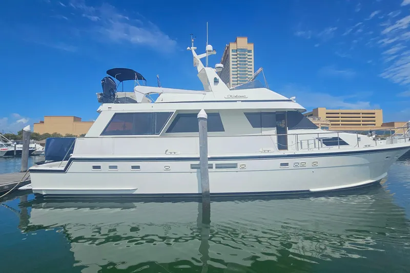 Slide: The Image of 1990 Hatteras 67 Cockpit Motor Yacht docked in a marina under clear blue skies. - 2