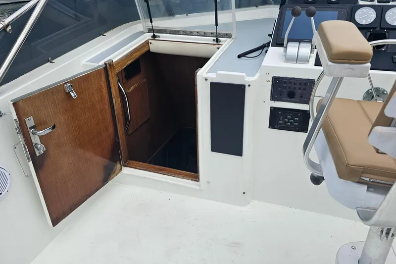 Slide: The Image of 1990 Hatteras 67 Cockpit Motor Yacht helm with open cabin door and control panel. - 32