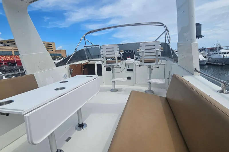 Slide: The Image of 1990 Hatteras 67 Cockpit Motor Yacht deck with seating and helm, docked at marina. - 39