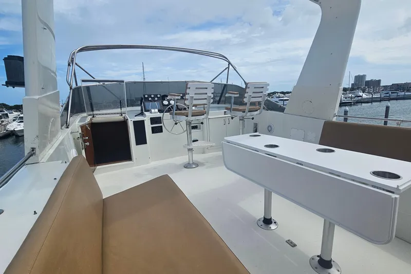 Slide: The Image of 1990 Hatteras 67 Cockpit Motor Yacht deck with seating and helm, docked at marina. - 40