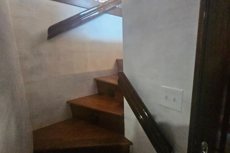 Slide: The Image of Wooden staircase inside 1990 Hatteras 67 Cockpit Motor Yacht, featuring polished handrails. - 42