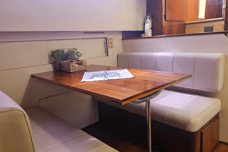 Slide: The Image of Interior of 1990 Hatteras 67 Cockpit Motor Yacht with wooden table and cushioned seating. - 51