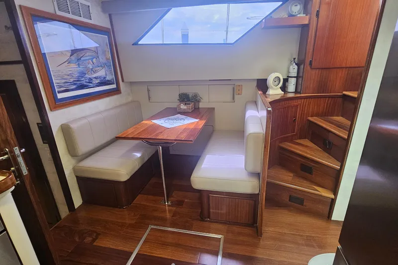 Slide: The Image of Interior of 1990 Hatteras 67 Cockpit Motor Yacht with dining area and wooden stairs. - 53