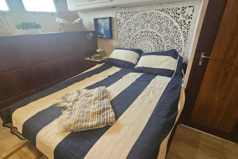 Slide: The Image of Cozy bedroom in 1990 Hatteras 67 Cockpit Motor Yacht with striped bedding and decorative wall art. - 57