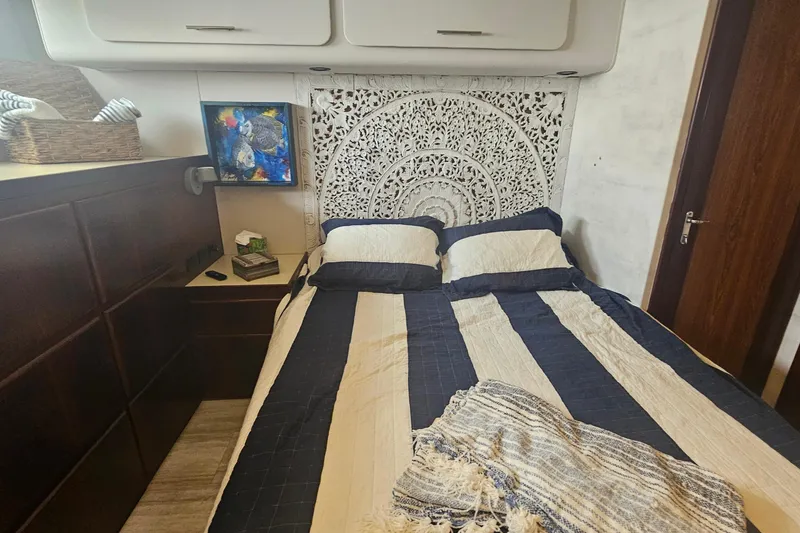 Slide: The Image of Cozy bedroom in 1990 Hatteras 67 Cockpit Motor Yacht with decorative headboard and striped bedding. - 58