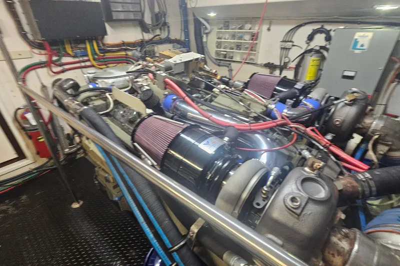 Slide: The Image of Engine room of a 1990 Hatteras 67 Cockpit Motor Yacht with visible machinery and wiring. - 75