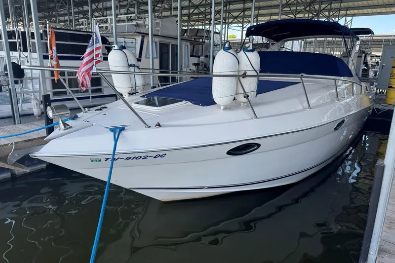 Slide: The Image of 2000 Regal Commodore 3260 boat docked with fenders and flags, covered in blue canvas. - 50