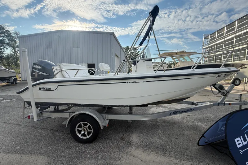 Slide: The Image of 2002 Boston Whaler 180 Dauntless boat on trailer, parked outdoors under a blue sky. - 11