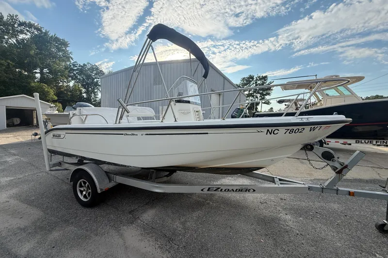 Slide: The Image of 2002 Boston Whaler 180 Dauntless boat on trailer, parked outdoors under a blue sky. - 12