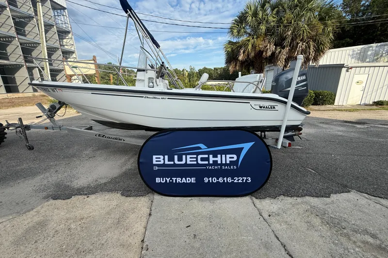 Slide: The Image of 2002 Boston Whaler 180 Dauntless boat on trailer, Bluechip Yacht Sales sign in foreground. - 17