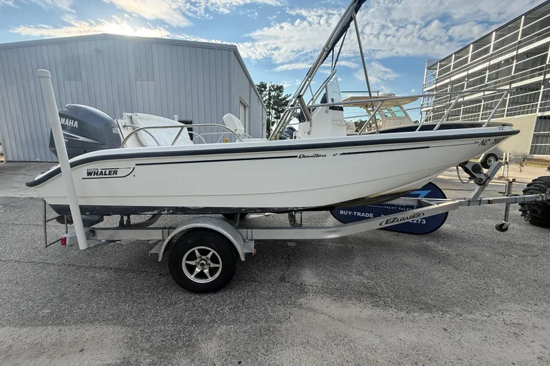 Slide: The Image of 2002 Boston Whaler 180 Dauntless boat on trailer, parked outdoors near a warehouse. - 7