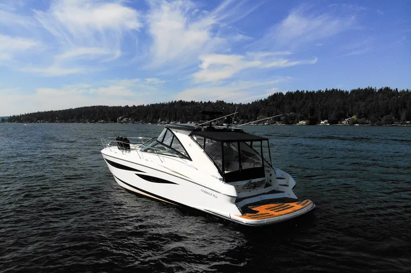 Slide: The Image of 2018 Cobalt 46 Yacht on serene lake with forested shoreline and blue sky. - 2