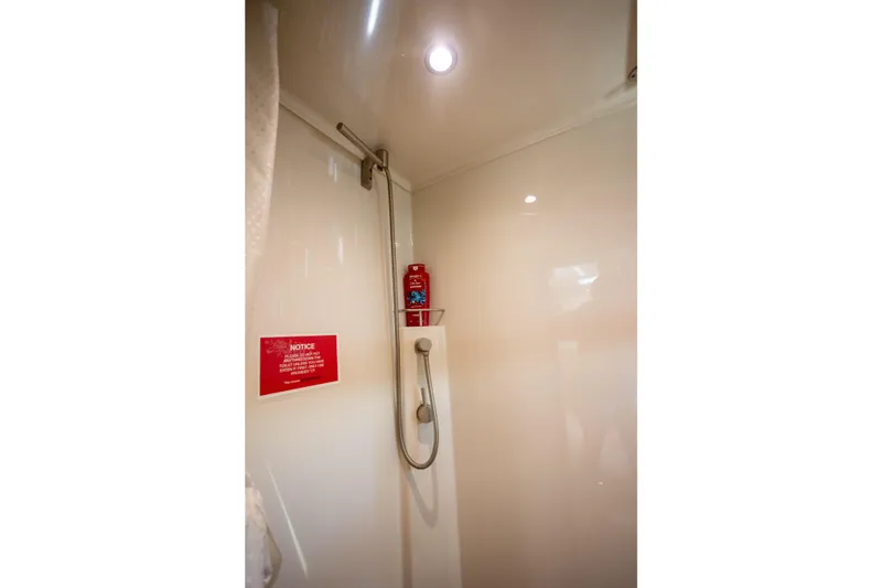 Slide: The Image of Shower area in 2018 Cobalt 46 Yacht with handheld showerhead and notice sign. - 27