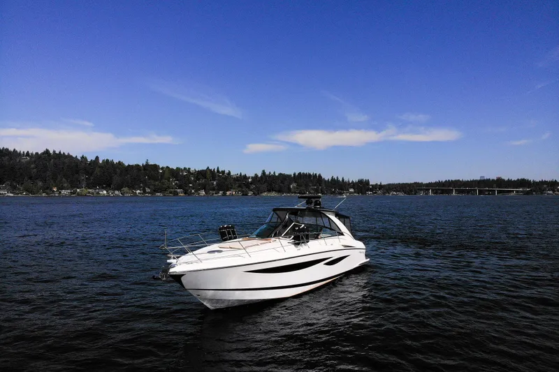 Slide: The Image of 2018 Cobalt 46 Yacht on serene lake with forested shoreline and clear blue sky. - 3