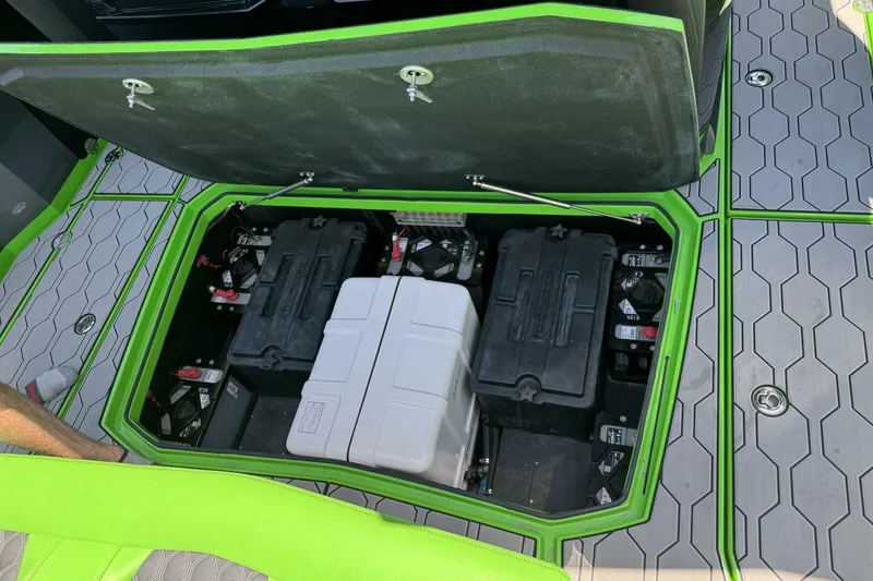 Slide: The Image of Open battery compartment of 2023 Adrenaline 47 boat with green trim and hexagonal flooring. - 14