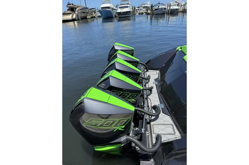 Slide: The Image of Four green and black 500R outboard motors on a 2023 Adrenaline 47 boat at a marina. - 8