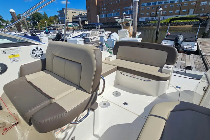 Slide: The Image of 2015 Sea Ray 260 Sundancer boat interior with beige seating at a marina. - 10