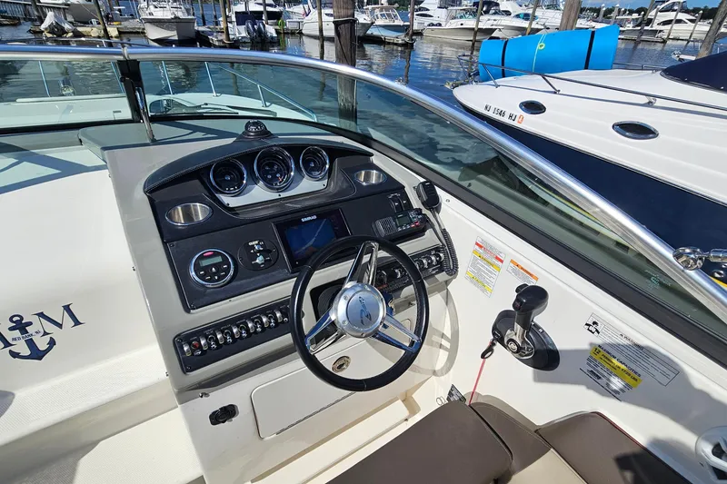 Slide: The Image of 2015 Sea Ray 260 Sundancer boat dashboard with steering wheel and controls at marina. - 11