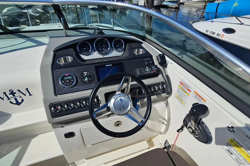 Slide: The Image of 2015 Sea Ray 260 Sundancer boat dashboard with steering wheel and control panel. - 12