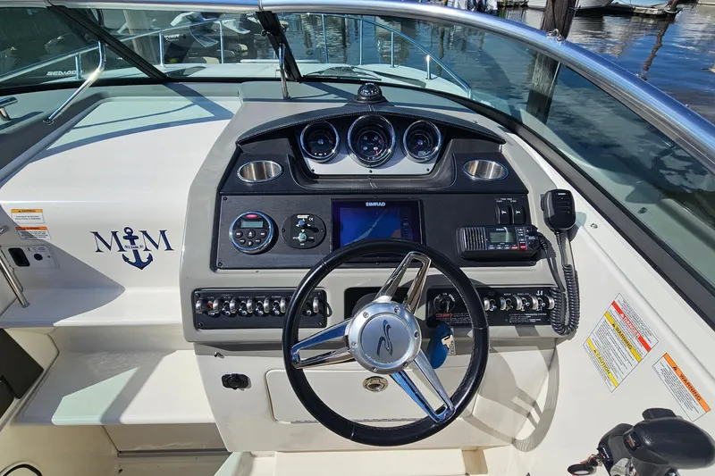 Slide: The Image of 2015 Sea Ray 260 Sundancer helm with steering wheel, gauges, and navigation equipment. - 13