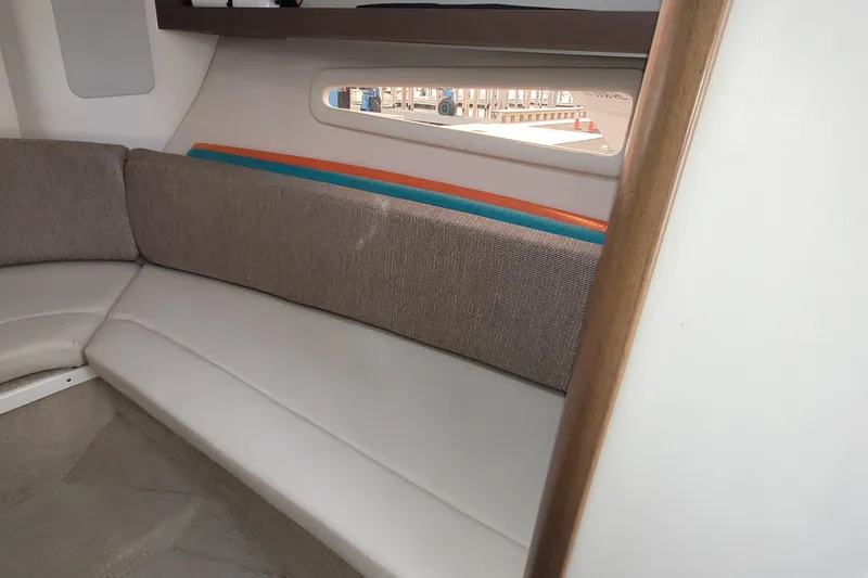 Slide: The Image of Interior of 2015 Sea Ray 260 Sundancer with cushioned seating and window view. - 19