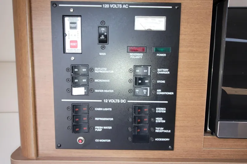 Slide: The Image of Control panel of a 2015 Sea Ray 260 Sundancer boat, featuring AC and DC switches. - 24