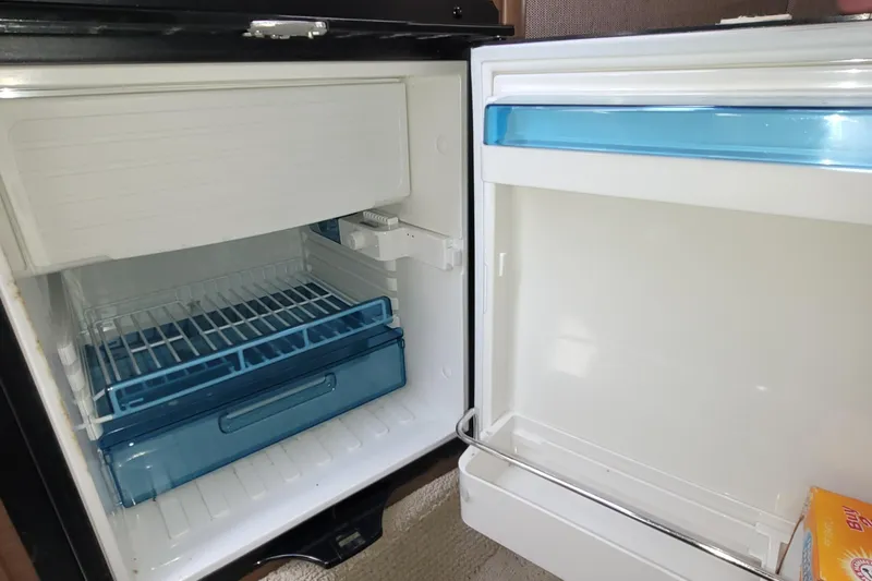 Slide: The Image of Open refrigerator inside a 2015 Sea Ray 260 Sundancer boat, showing empty shelves and compartments. - 26