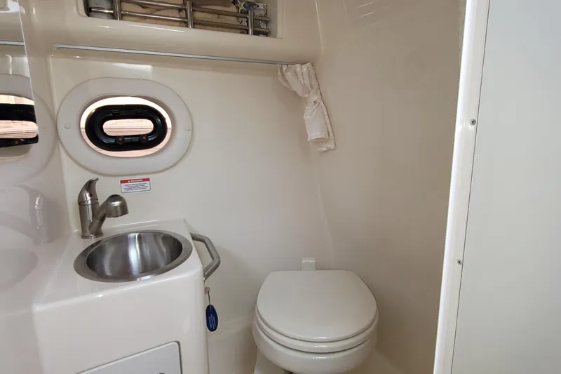 Slide: The Image of 2015 Sea Ray 260 Sundancer bathroom with sink, toilet, and porthole window. - 28