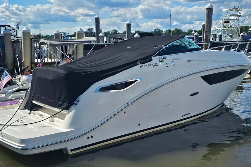 Slide: The Image of 2015 Sea Ray 260 Sundancer boat docked with black cover, under blue sky. - 4