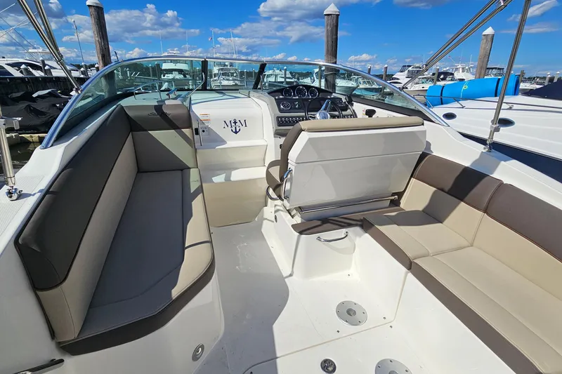 Slide: The Image of 2015 Sea Ray 260 Sundancer boat interior with seating and dashboard, docked under a blue sky. - 6