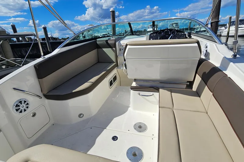 Slide: The Image of 2015 Sea Ray 260 Sundancer boat interior with beige seating and dashboard, docked under blue sky. - 8