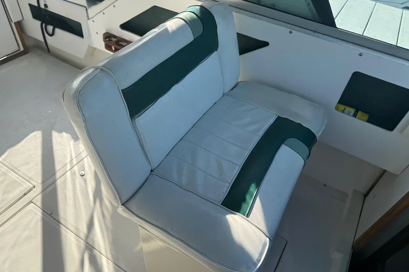 Slide: The Image of 1989 Sea Ray 300 Weekender interior with white and green cushioned seating. - 12