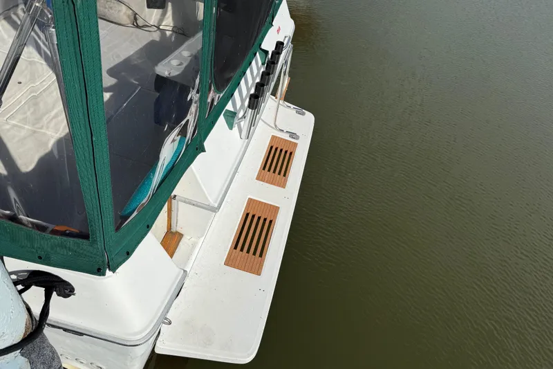 Slide: The Image of 1989 Sea Ray 300 Weekender boat with green canopy, docked on calm water. - 15