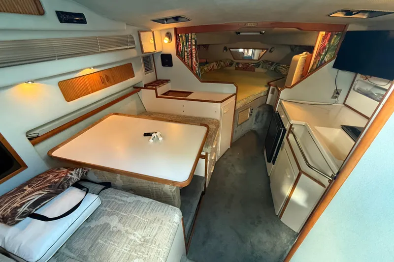 Slide: The Image of 1989 Sea Ray 300 Weekender cabin interior with dining area, kitchenette, and sleeping quarters. - 18