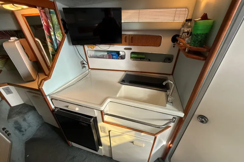 Slide: The Image of 1989 Sea Ray 300 Weekender boat interior with kitchenette, sink, and mounted TV. - 25