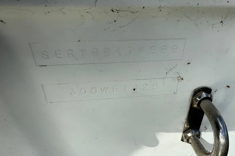 Slide: The Image of 1989 Sea Ray 300 Weekender hull identification number and metal cleat on white surface. - 33