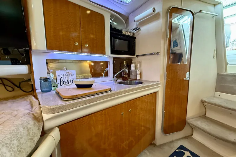 Slide: The Image of 2002 Regal Commodore 2860 boat interior with kitchenette, sink, microwave, and cozy decor. - 14