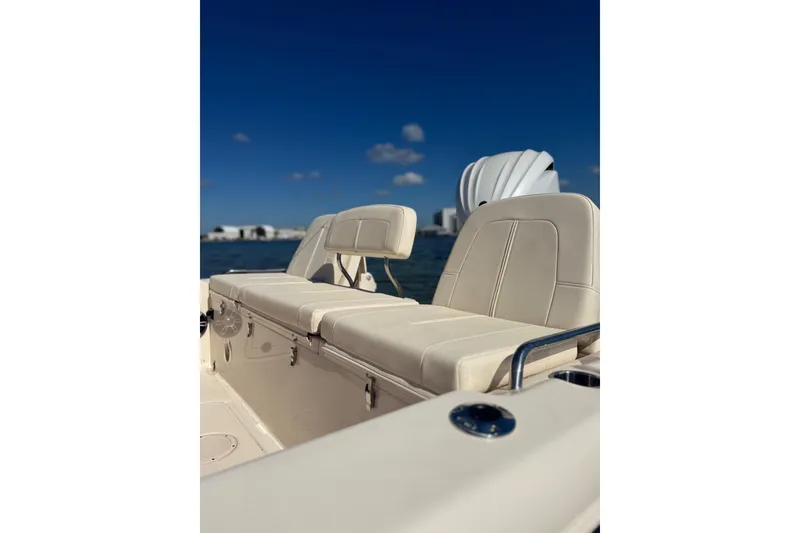 Slide: The Image of 2023 Grady-White 251 Coastal Explorer boat interior with beige seating, under clear blue sky. - 12
