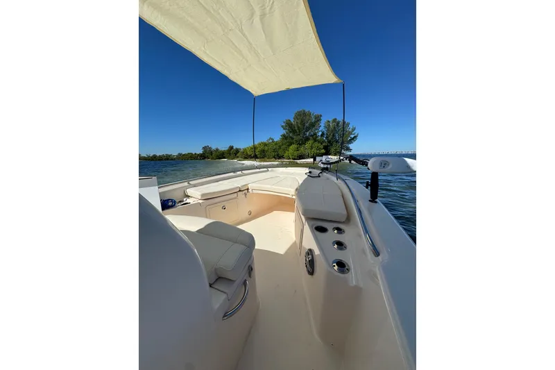 Slide: The Image of 2023 Grady-White 251 Coastal Explorer boat interior with canopy, on calm water near lush shoreline. - 5