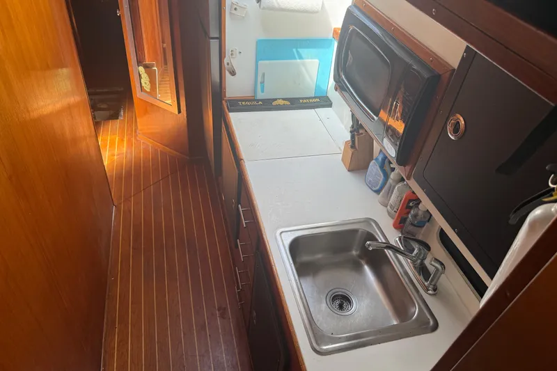 Slide: The Image of 1974 Pacemaker 48 Sportfisherman kitchen area with sink, microwave, and wooden flooring. - 27