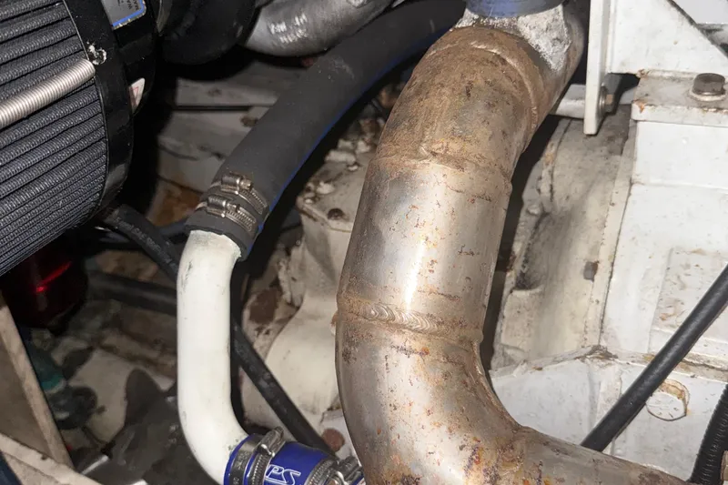 Slide: The Image of Engine components of a 1974 Pacemaker 48 Sportfisherman boat, featuring hoses and metal pipes. - 40