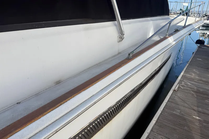Slide: The Image of 1974 Pacemaker 48 Sportfisherman yacht docked, showcasing sleek side view and railing. - 6