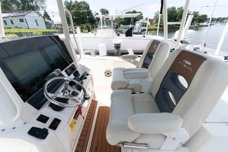 Slide: The Image of 2020 Cobia 320 Center Console boat with seating and twin outboard motors on a calm lake. - 12