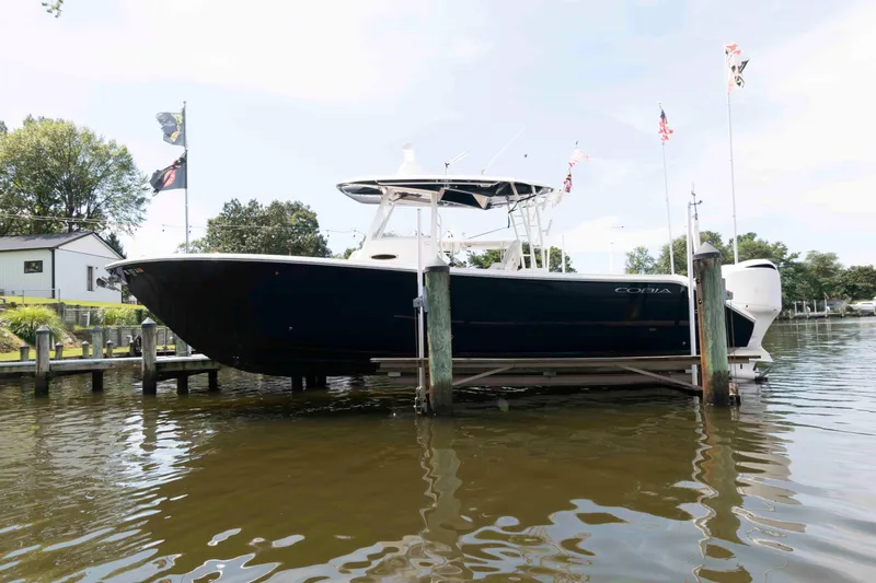 Slide: The Image of 2020 Cobia 320 Center Console boat docked with flags, on a sunny day. - 2