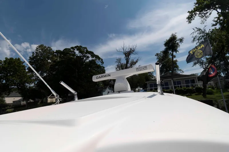 Slide: The Image of 2020 Cobia 320 Center Console boat docked by a serene lake. - 22