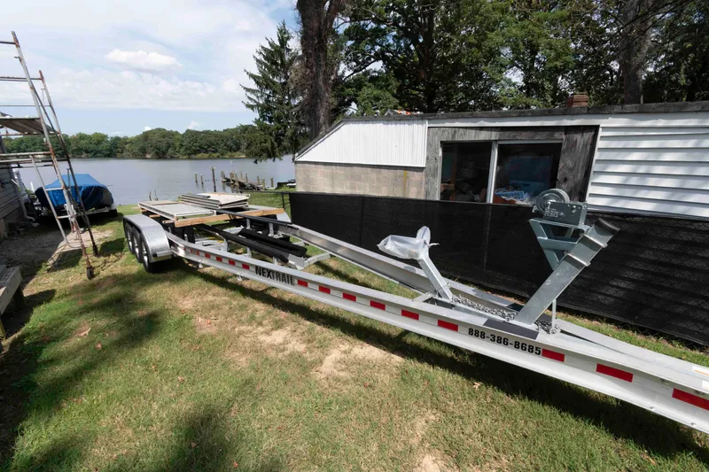 Slide: The Image of Triple-axle trailer for 2020 Cobia 320 Center Console, parked on grass near a lake. - 33